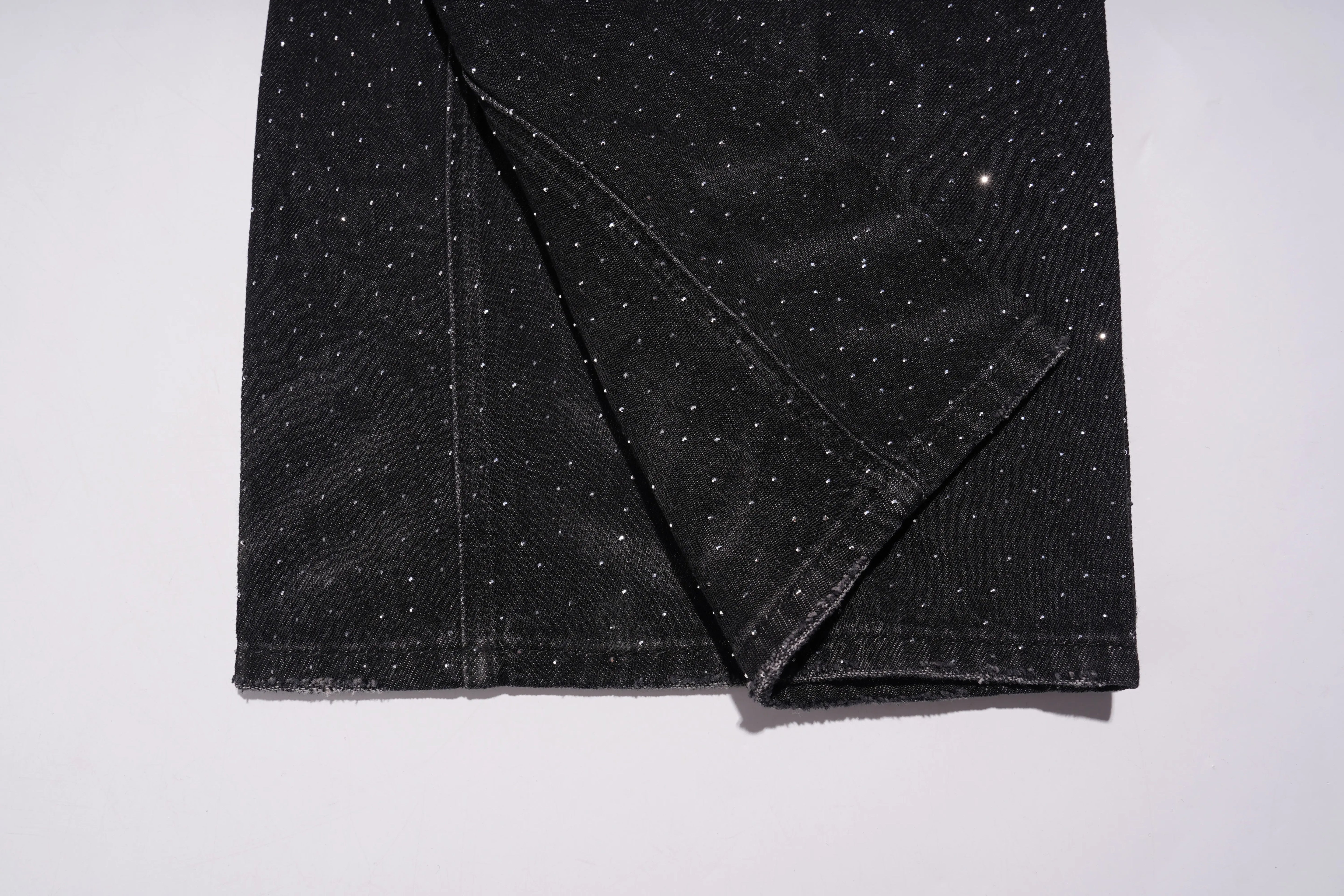 Folded black fabric with white speckles on a white background, TCH Starry Rhinestone Logo Black Denim Jeans