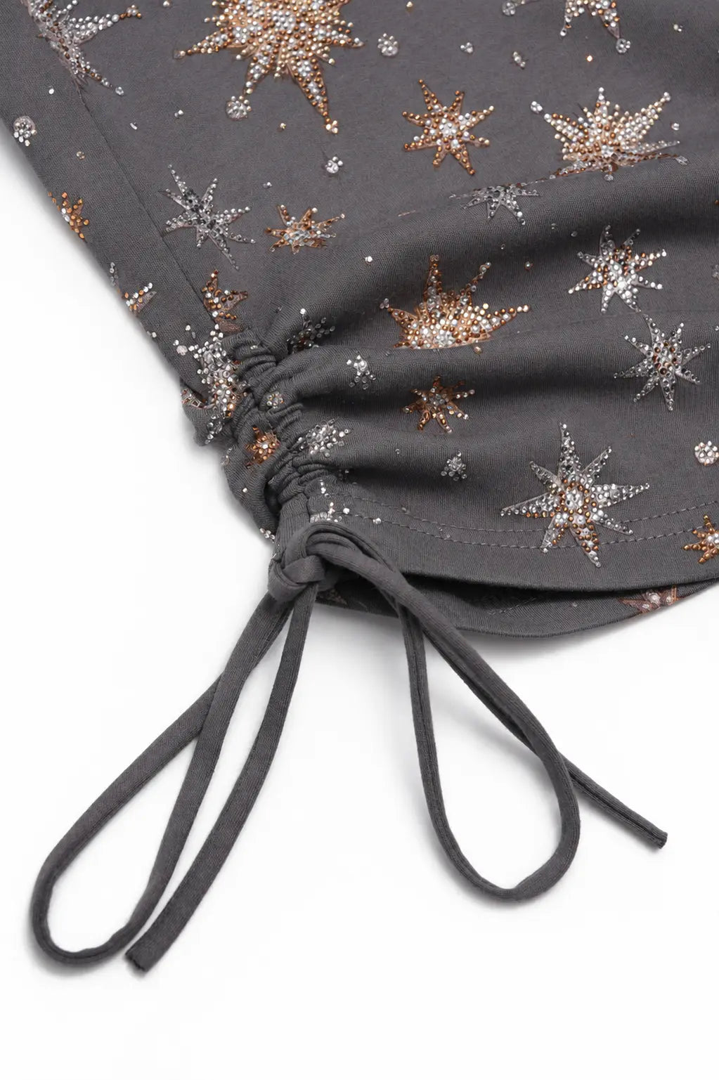 Close-up of a dark gray fabric garment with an allover metallic star and crown pattern, featuring a gathered side and drawstring tie, on a white background. TCH Starry Rhinestone Print Ruched Long Sleeve Top