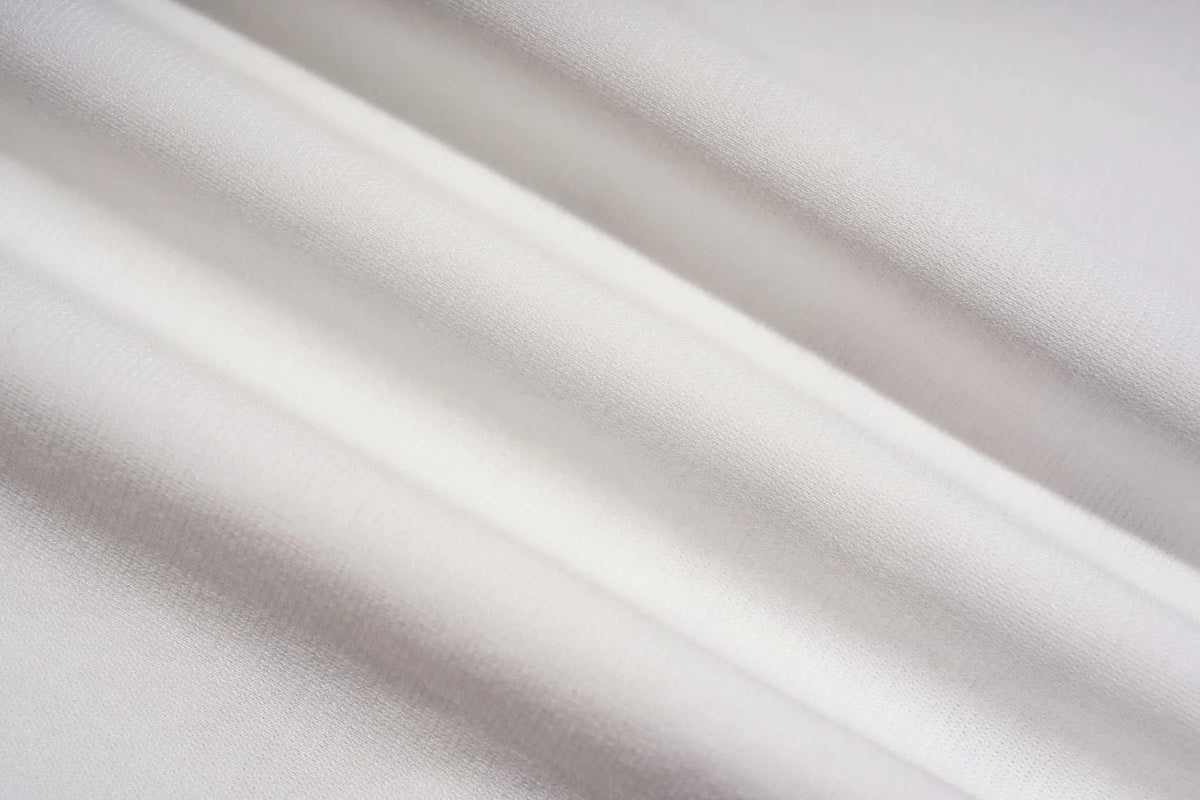 A close-up of draped white fabric with soft folds and a fine woven texture. TCH Starry Western Graphic White Long Sleeve Top