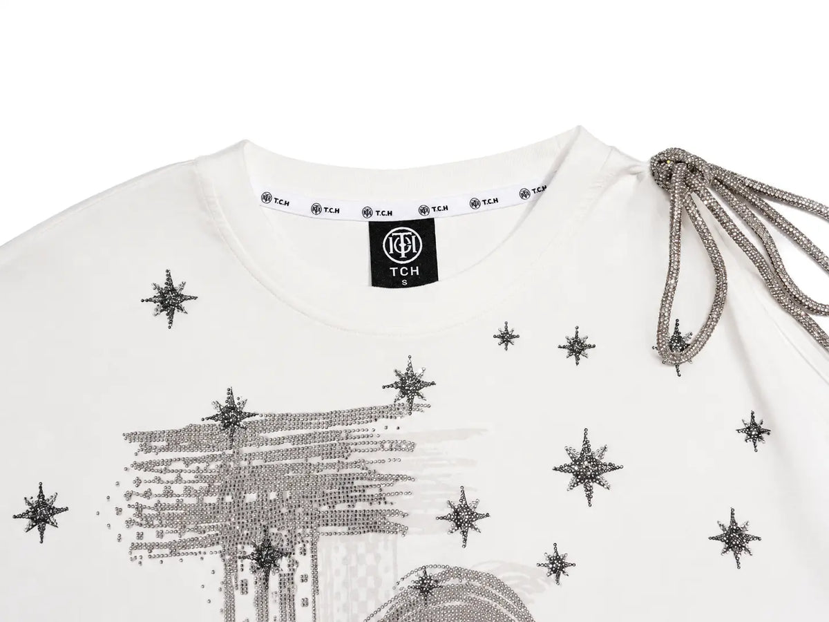 Close-up of a white TCH brand sweatshirt featuring silver rhinestone star prints and a rhinestone-embellished graphic on the front, with a silver rhinestone drawstring detail on the right shoulder. TCH Starry Western Graphic White Long Sleeve Top