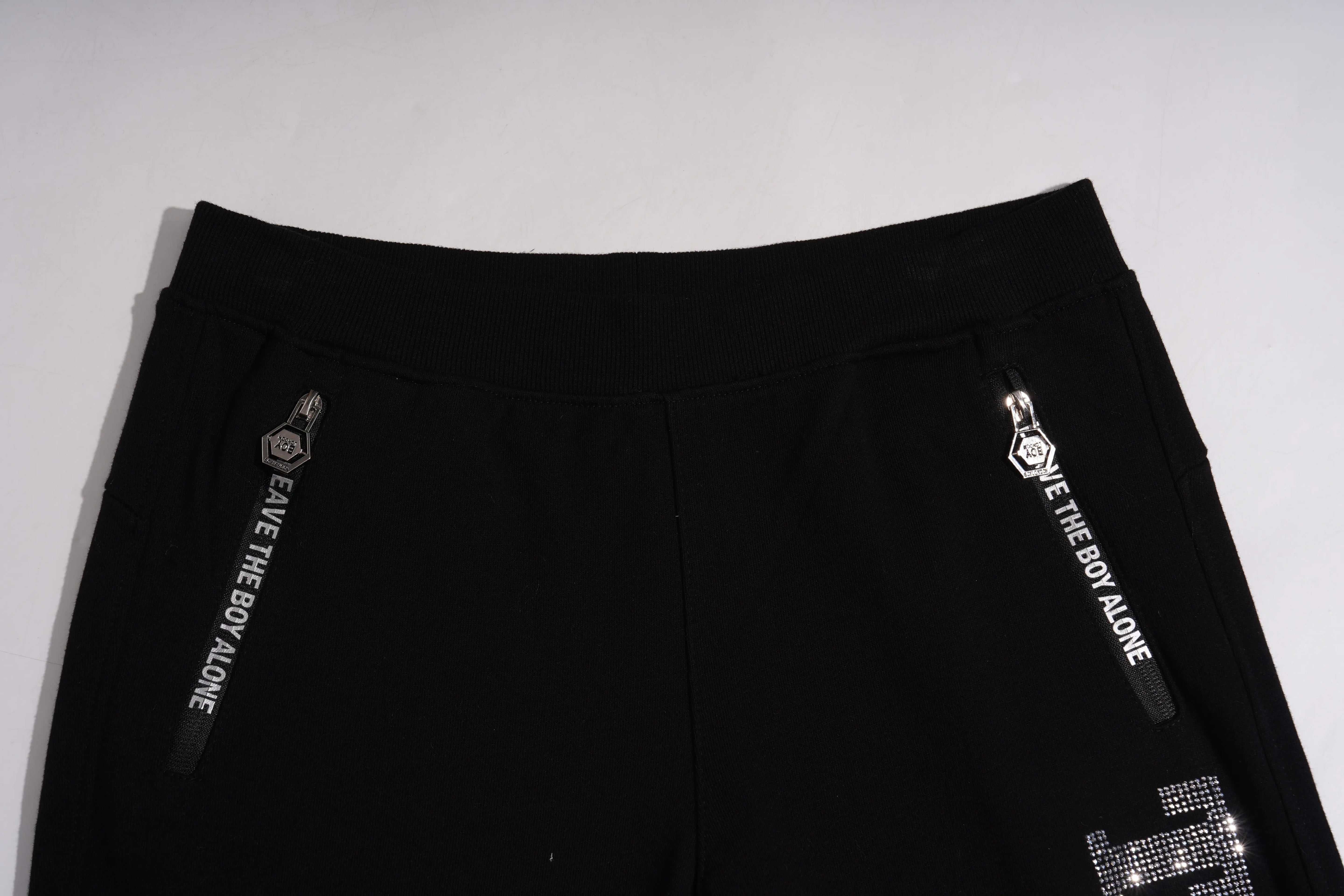 Black pants with white text and logo on a light gray background, TCH TECHNO Rhinestone Jogger Pants