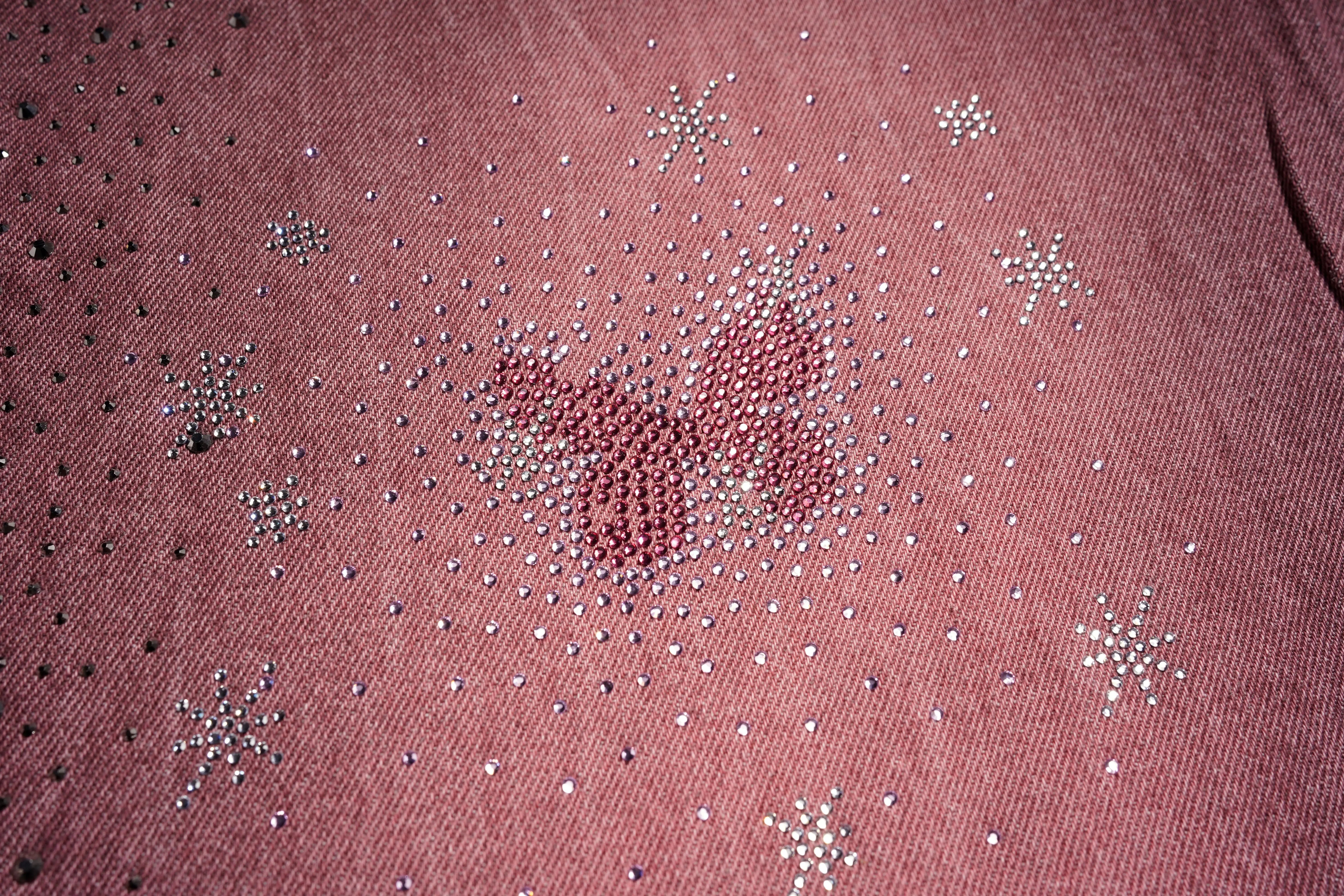 Close-up of a pink fabric with star-shaped embellishments, TCH Techno Butterfly Rhinestone Burgundy Jeans