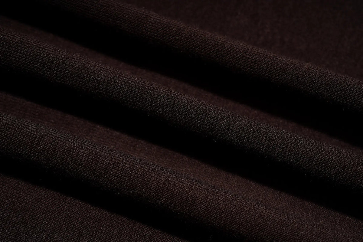 A close-up of dark brown ribbed knit fabric with soft diagonal folds and a smooth texture. TCH Techno Butterfly Starburst Graphic Long Sleeve Top