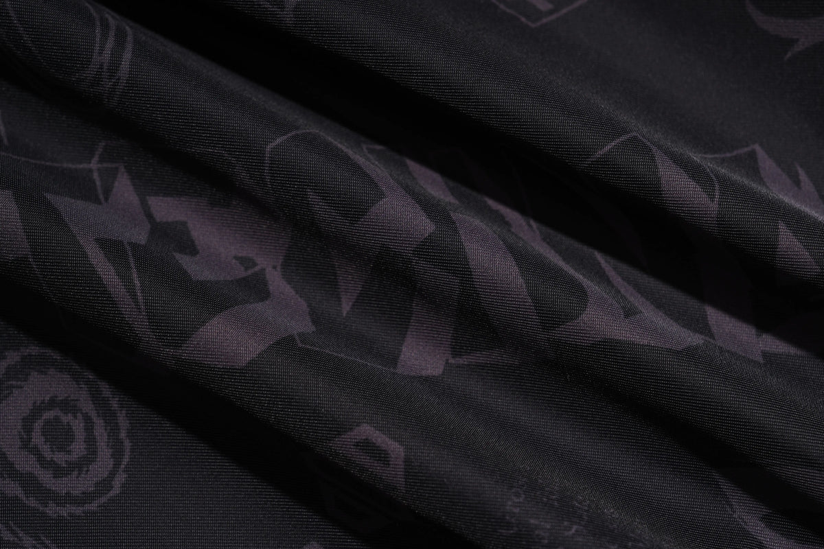 A close-up of draped black fabric with a subtle dark purple abstract pattern. TCH Techno Logo Wide-Leg Cargo Pants