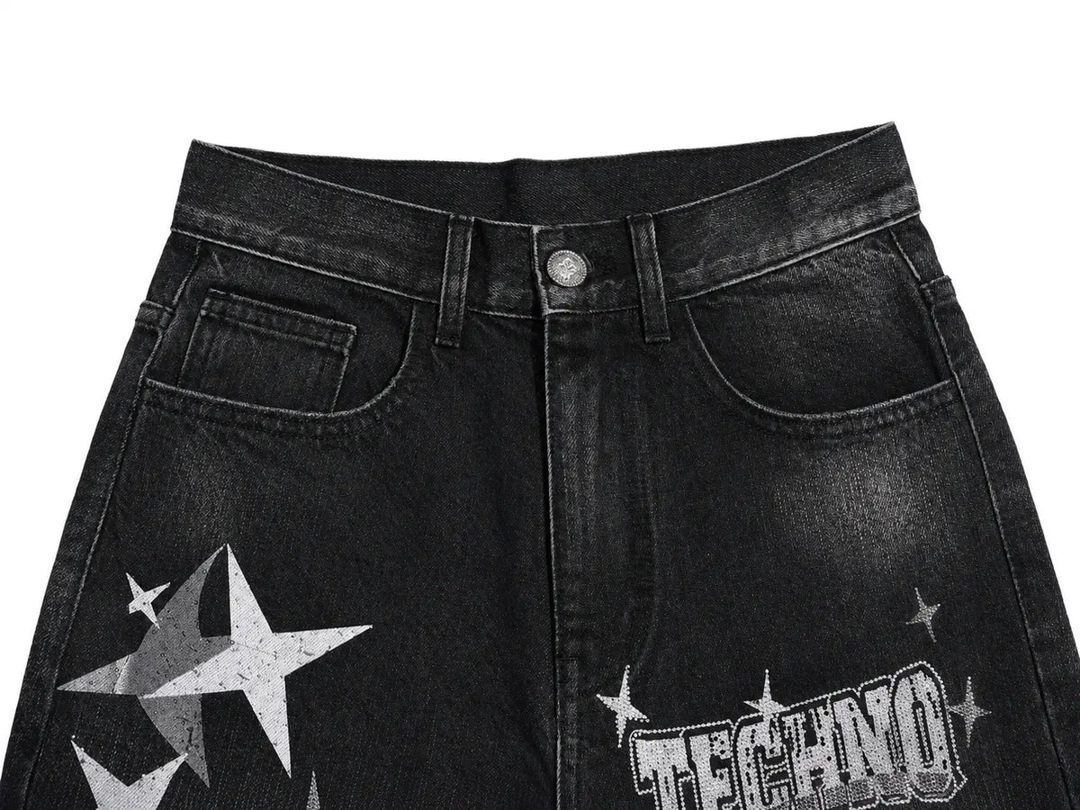Black washed denim jeans featuring a distressed white star graphic on the left thigh and a white 'TECHNO' logo with stars on the right leg, shown against a plain white background. TCH Techno Magic Star Graphic Wide-Leg Jeans