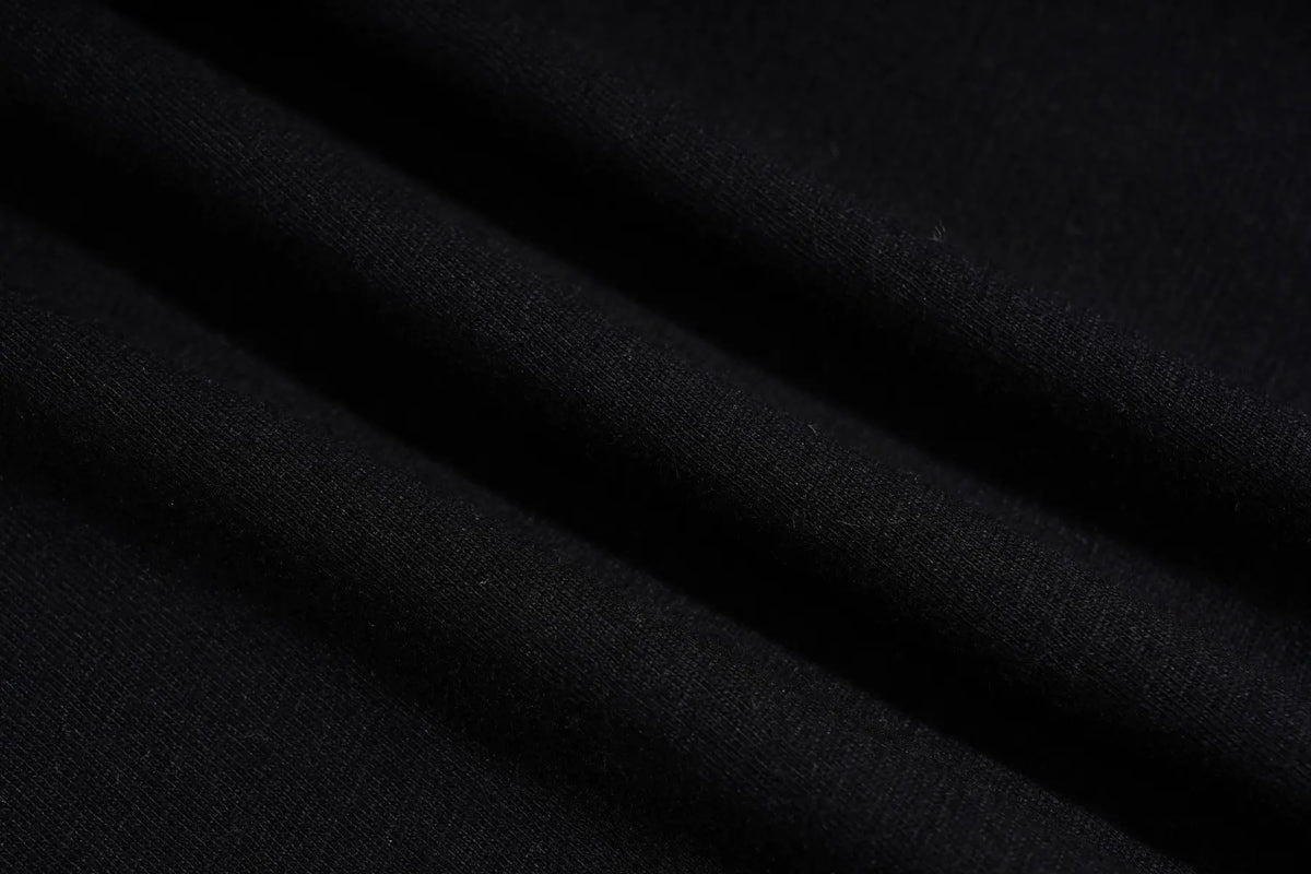 A close-up of draped black fabric with soft folds and a fine knit texture. TCH Techno Rhinestone Angel Wings Lace Trim Off-Shoulder Top