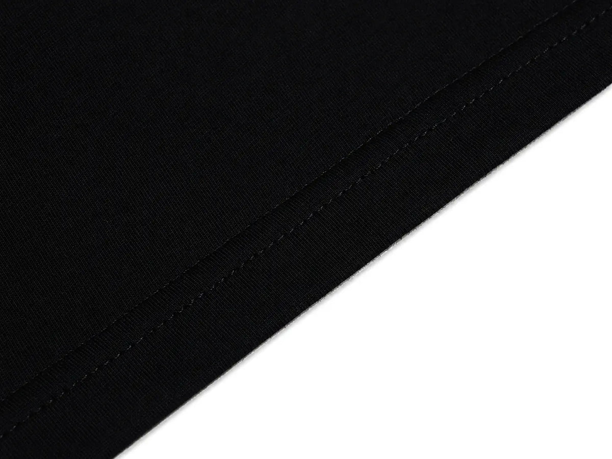 A close-up of a black ribbed fabric or material sample with a diagonal cut edge against a white background. TCH Techno Rhinestone Gothic Graphic Black T-Shirt