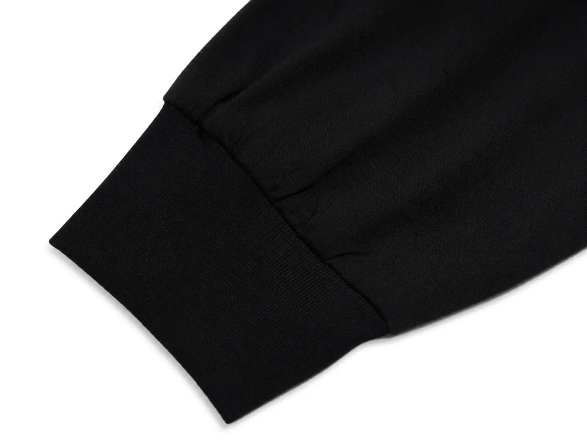 Close-up detail of a black ribbed knit cuff on a white background. TCH Techno Teddy Graphic Raglan Long Sleeve Shirt