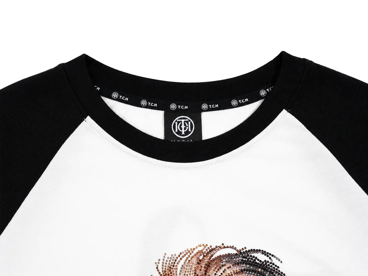 Close-up of a raglan baseball t-shirt with a white body and black sleeves, featuring a black neck label with the TCH logo and a metallic rose gold sequin graphic on the front. TCH Techno Teddy Graphic Raglan Long Sleeve Shirt