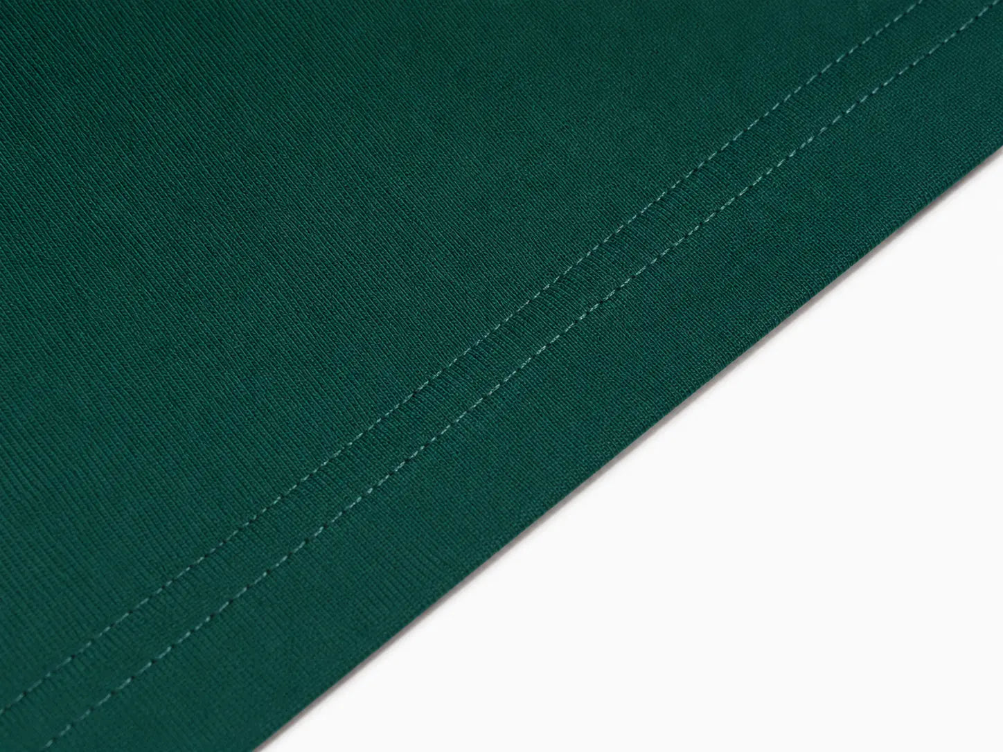 Close-up of a dark green fabric surface with a diagonal stitched edge against a white background. TCH Teddy Bear Rhinestone Graphic T-Shirt