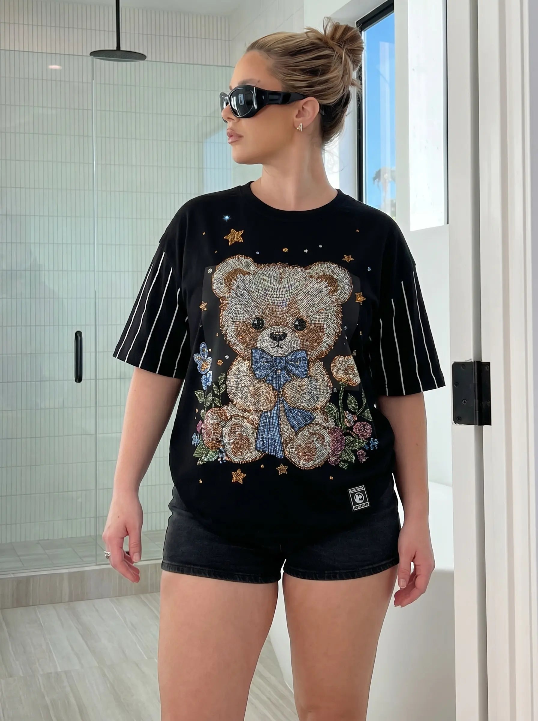 Woman wearing a black t-shirt with a teddy bear design in a modern indoor setting, TCH Teddy Bear & Stars Rhinestone T-Shirt