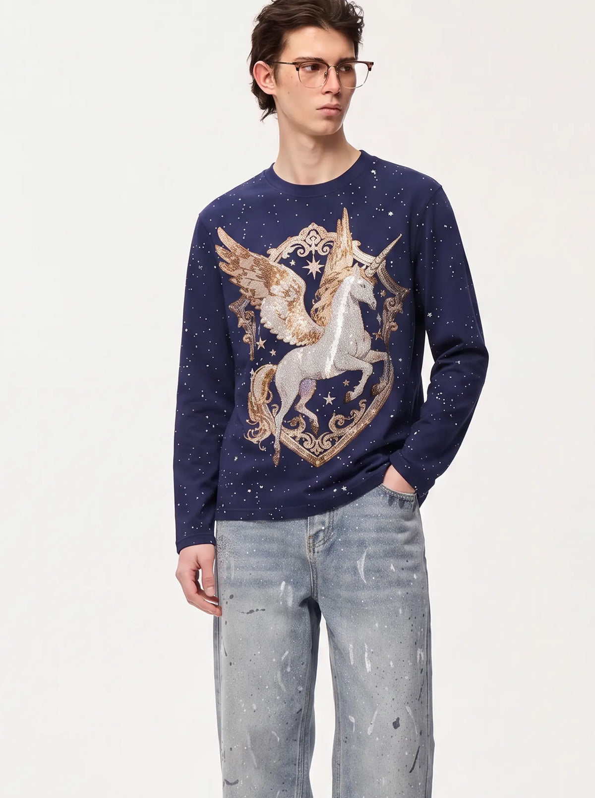 A man wearing a navy blue long-sleeve sweater with a large metallic gold and silver unicorn graphic on the front, paired with light-wash jeans, against a plain white studio background. TCH Winged Unicorn Starry Rhinestone Long Sleeve T-Shirt