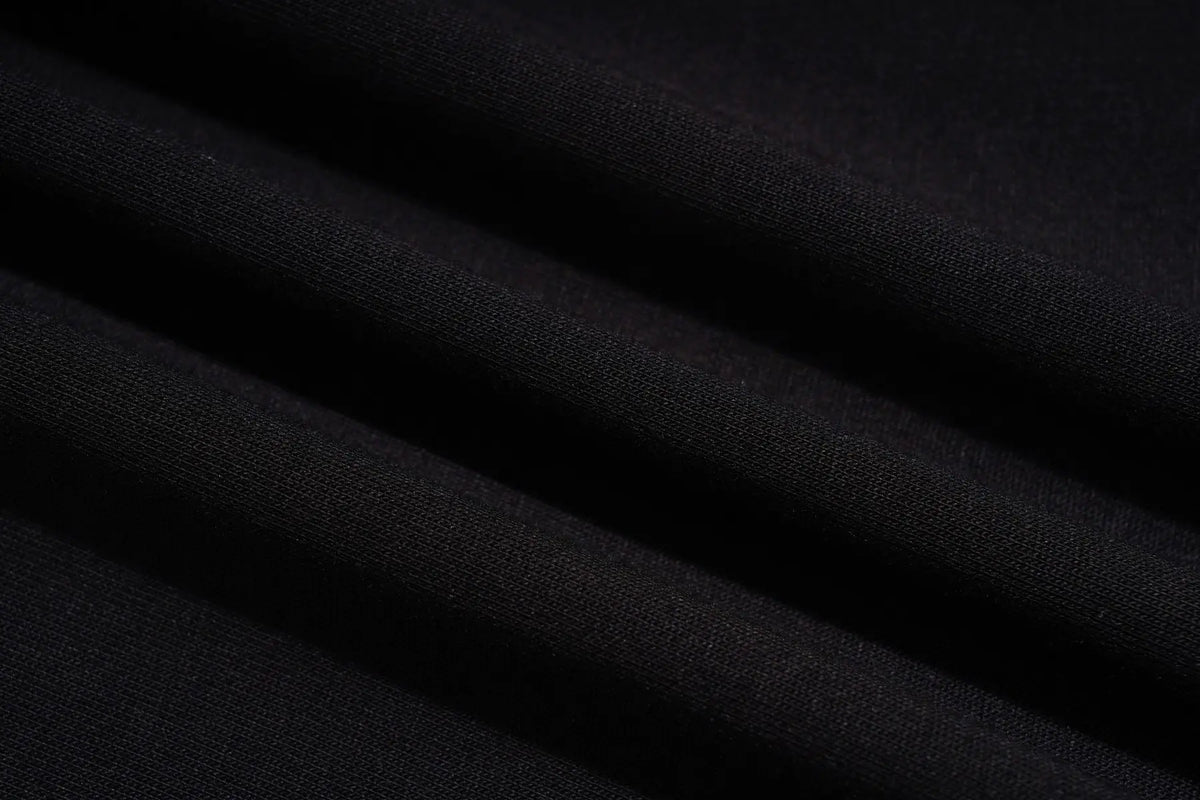 A close-up of draped black fabric with soft folds showing a fine knit texture. TCH Women’s Black Wide-Leg Sweatpants with Rhinestone Star Graphic