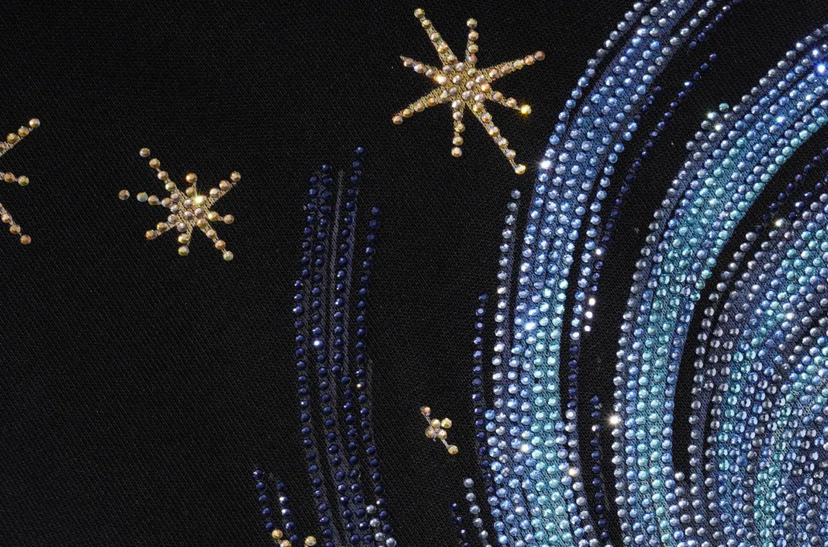 Close-up of a black embellished surface with gold starburst motifs and curved rows of blue and silver rhinestones. TCH Women’s Black Wide-Leg Sweatpants with Rhinestone Star Graphic