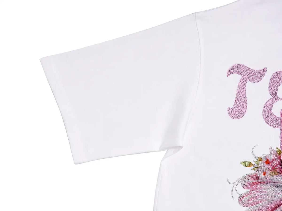 Close-up of a white short-sleeve T-shirt showing part of a pink rhinestone graphic with decorative lettering and floral embellishments on a white background. TCH Women's Pink Angel Graphic Oversized T-Shirt