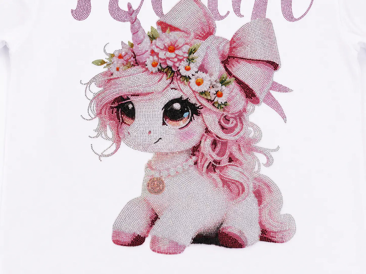 A close-up of a white garment featuring a pink cartoon unicorn graphic with a floral crown, large eyes, and a matching pink bow, with partial decorative text above. TCH Women's Pink Angel Graphic Oversized T-Shirt