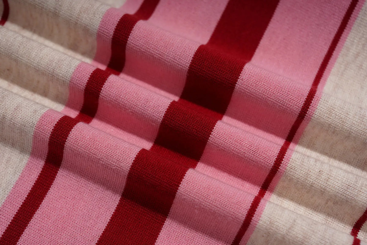 A close-up of a woven textile with alternating wide pink and narrow dark red stripes on a light beige base, shown in soft folds. TCH Women's Striped Polo Mini Dress