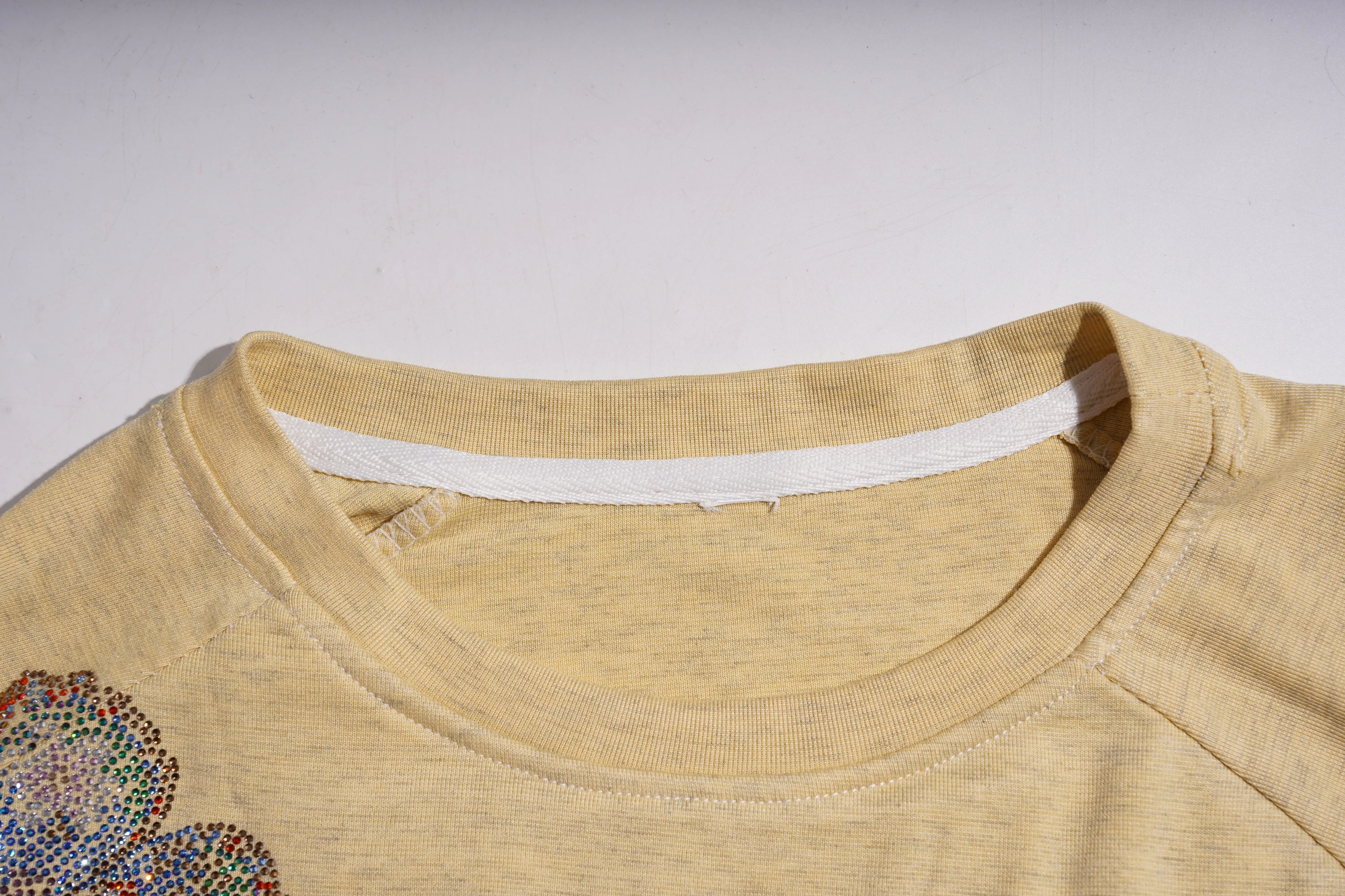 Close-up of a beige garment with a floral embellishment on a light gray background, TCH Yellow Butterfly Pajama Set