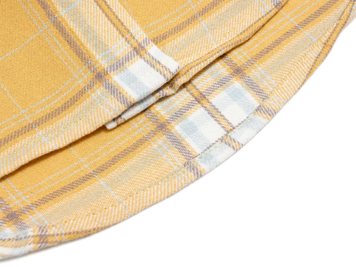 Close-up of a folded plaid fabric in a mustard yellow, white, and light gray pattern on a white background. TCH Yellow Plaid Embroidered Cross Shirt